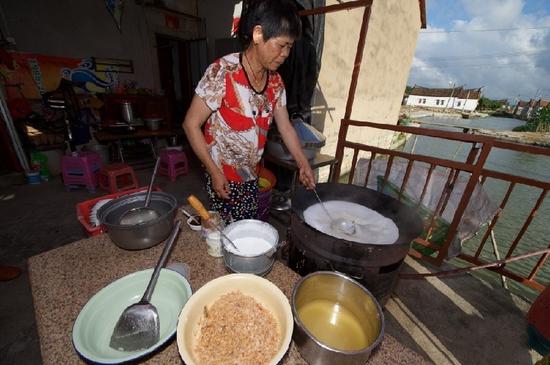 　5月27日，埭美村一位經營小吃店的村民在為游客做當地美食“鍋邊糊”