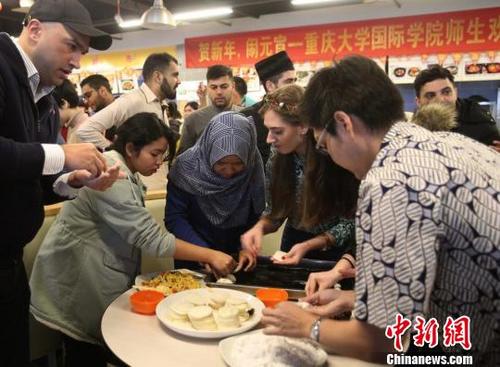 中國僑網圖為重慶大學留學生包餃子和湯圓共慶元宵節。　鐘欣　攝