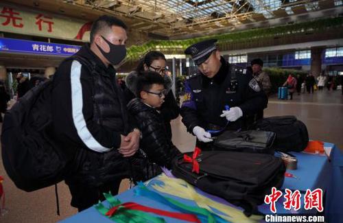 12月28日，北京西站派出所民警為背黑色雙肩包的旅客系上個性小標識，以防在通過安檢或乘車過程中出現錯拿情況。(完) 龐賀雷 攝