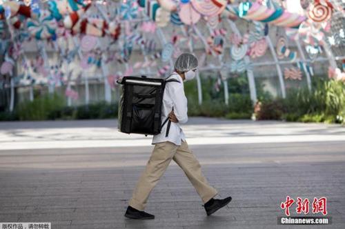 資料圖：當?shù)貢r間2021年1月4日，泰國曼谷，一名快遞員“全副武裝”走在街頭。